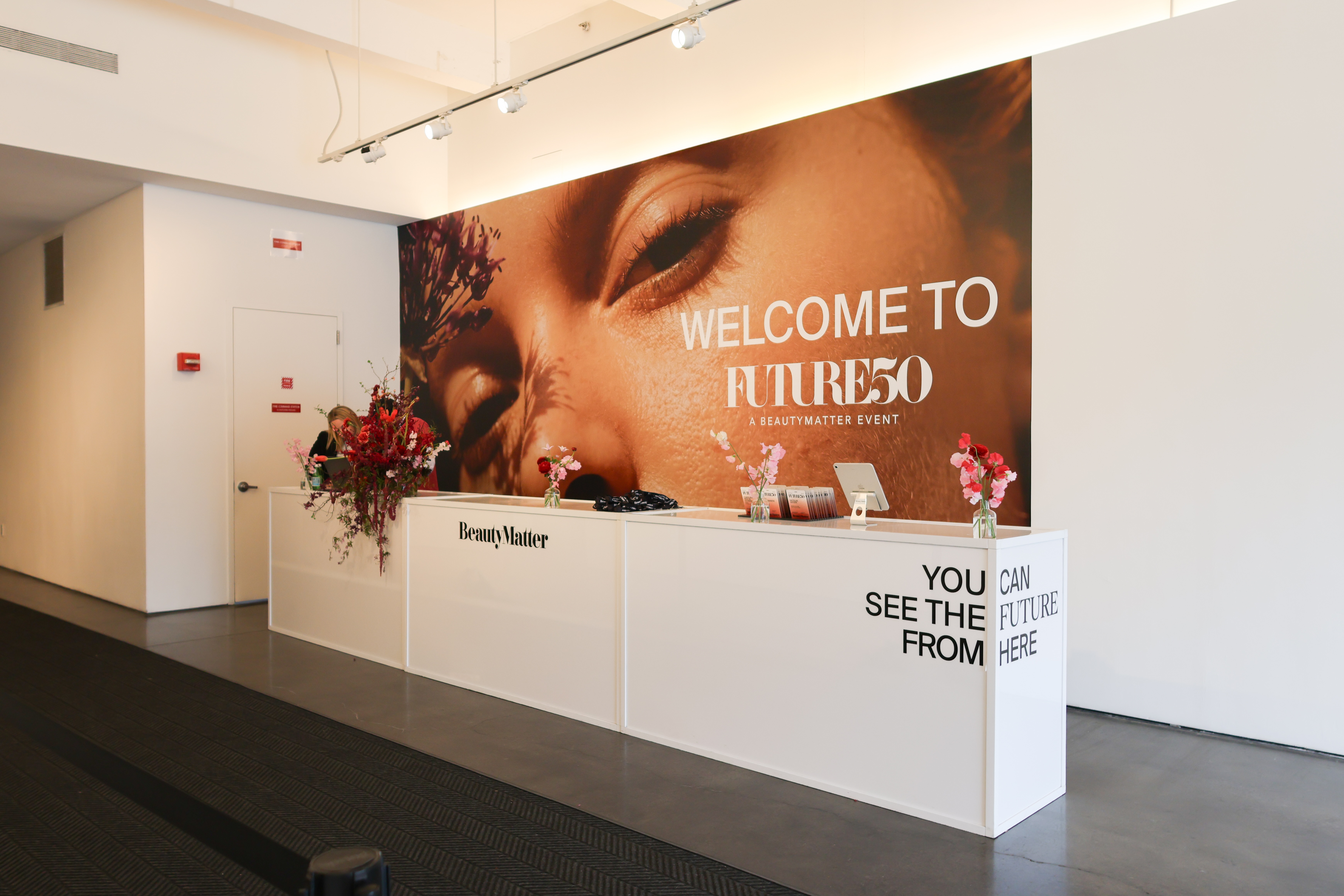 Event check-in desk with “Welcome to Future50” BeautyMatter branding and large mural backdrop.