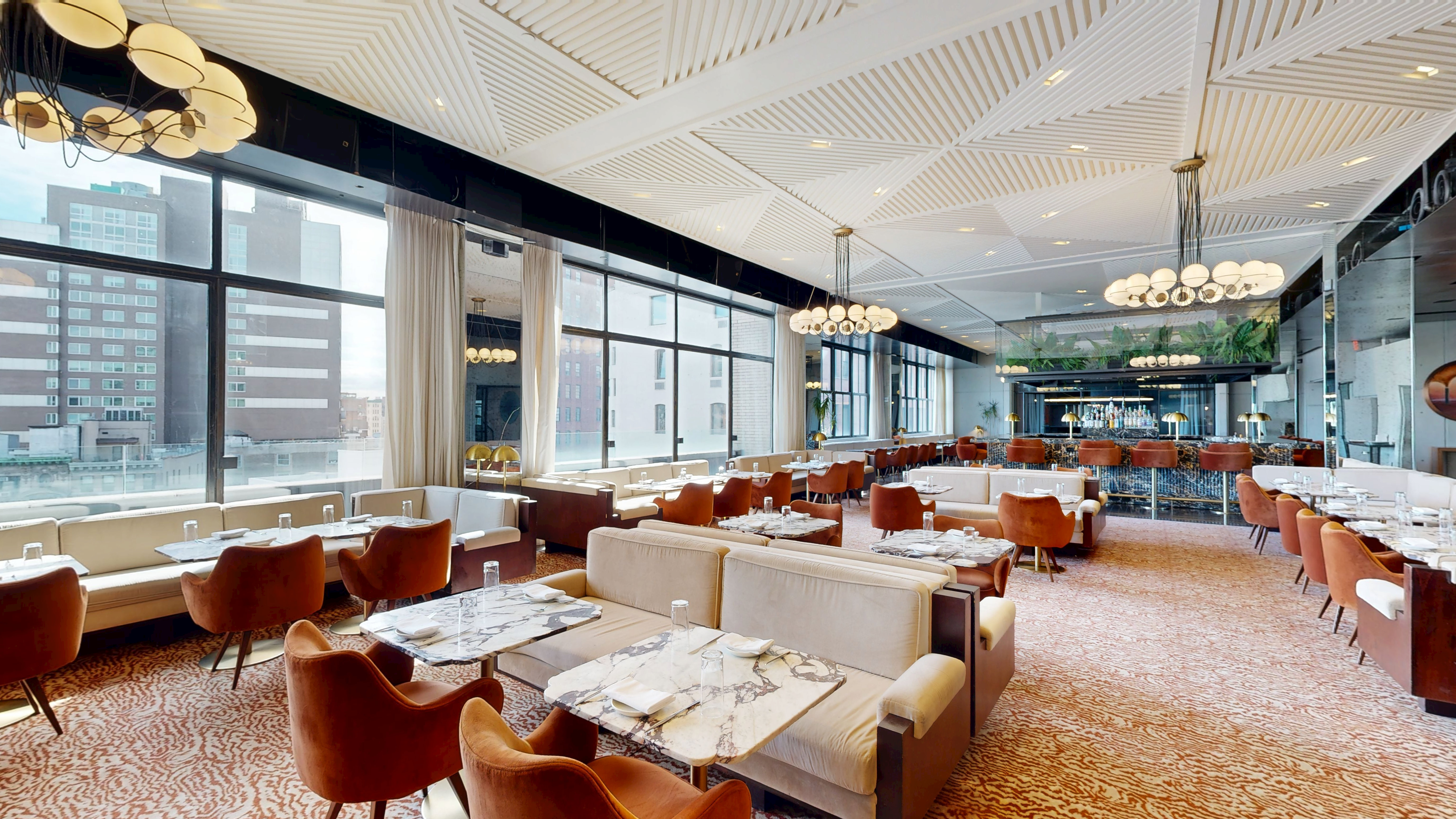 Wide view of the restaurant dining room with modern furniture and soft lighting.
