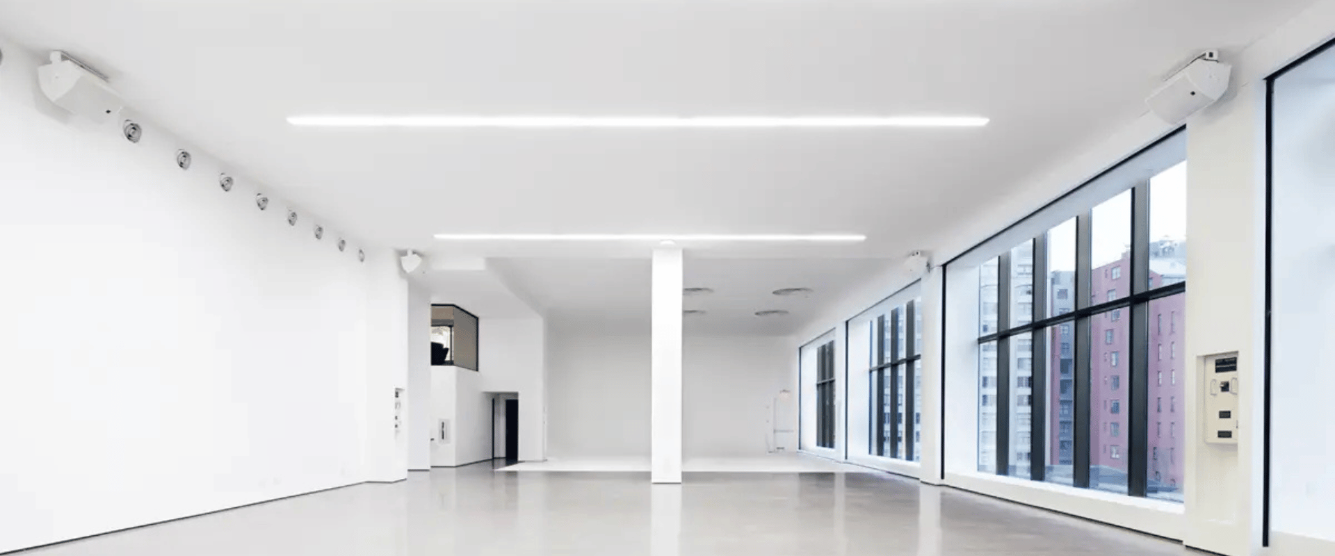 Minimalist open-plan wellness studio rental in NYC with polished floors, sleek lighting, and natural city light