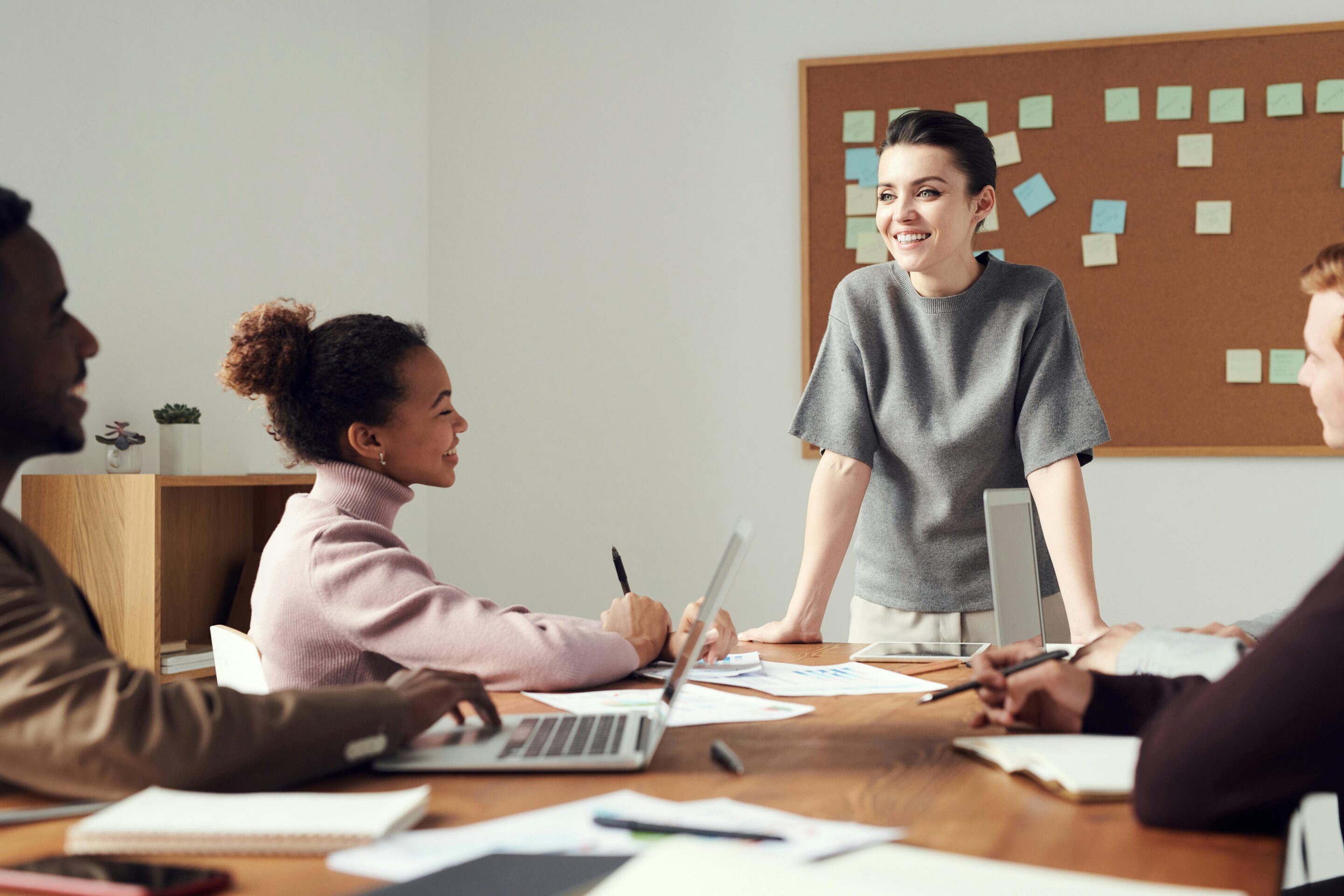 Mehrere Personen sitzen gemeinsam am Tisch, arbeiten und lächeln – Symbol für mentale Gesundheit am Arbeitsplatz