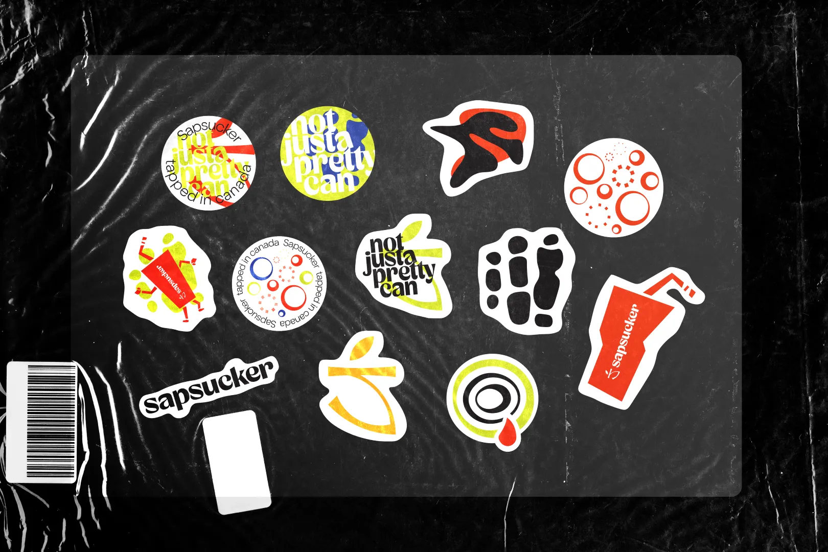 A variety of playful Sapsucker logo and graphic stickers displayed on a black plastic surface.