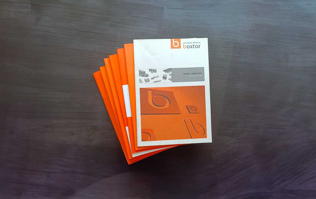 Stack of orange and white Boxtar product catalogs on a wooden surface.
