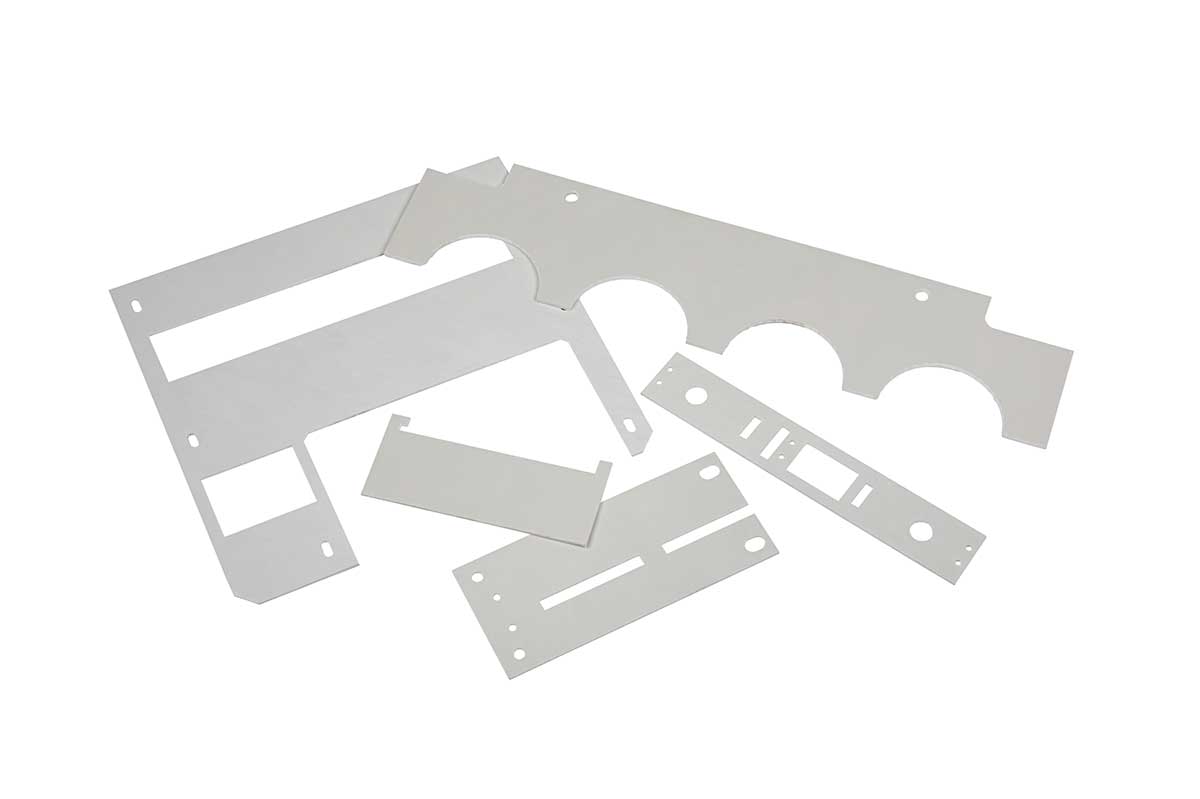 Set of white custom-cut plastic or metal sheet parts with various holes and slots.