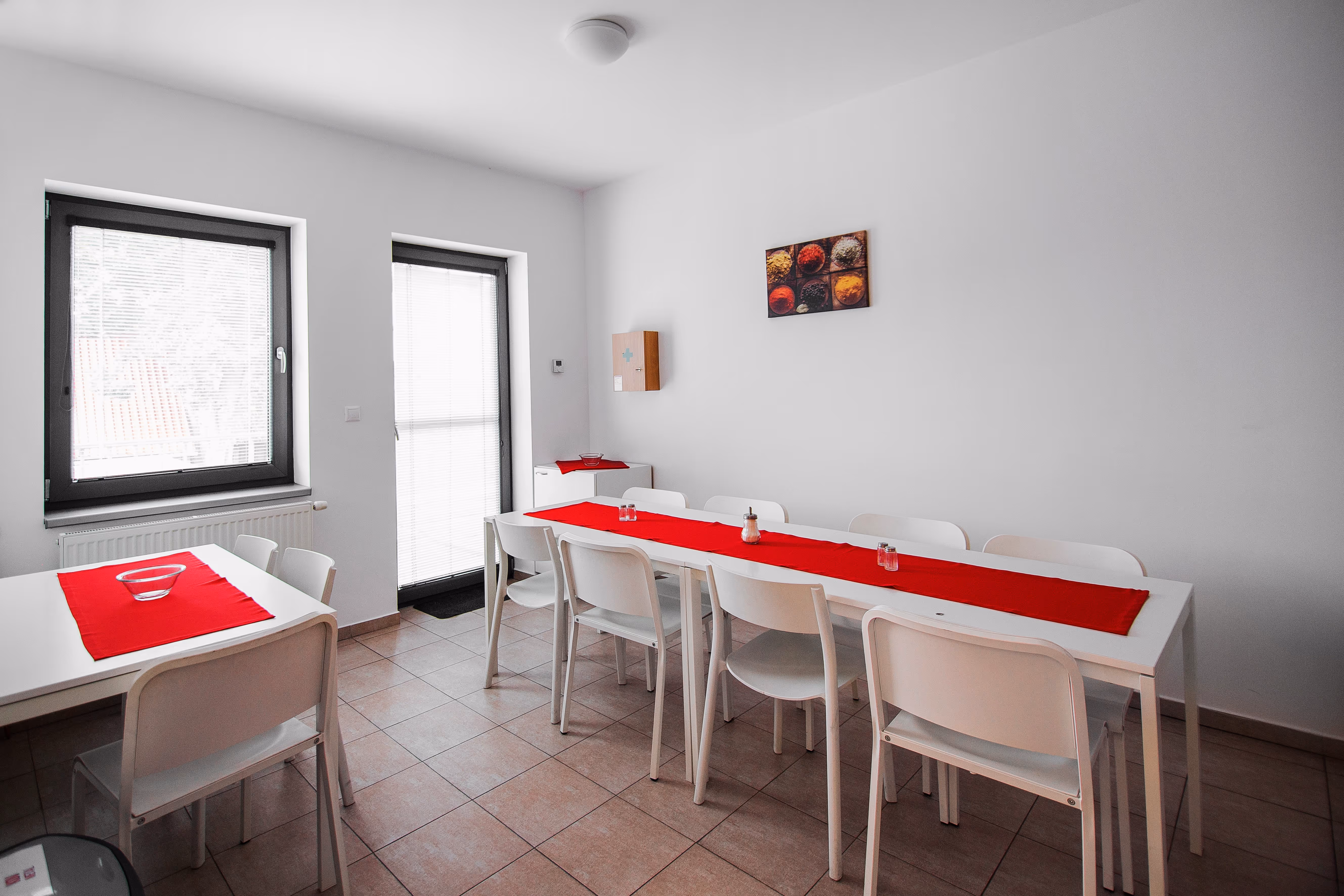 Bočný pohľad na kuchynku s jedálenskými stôlmi a dverami na balkón