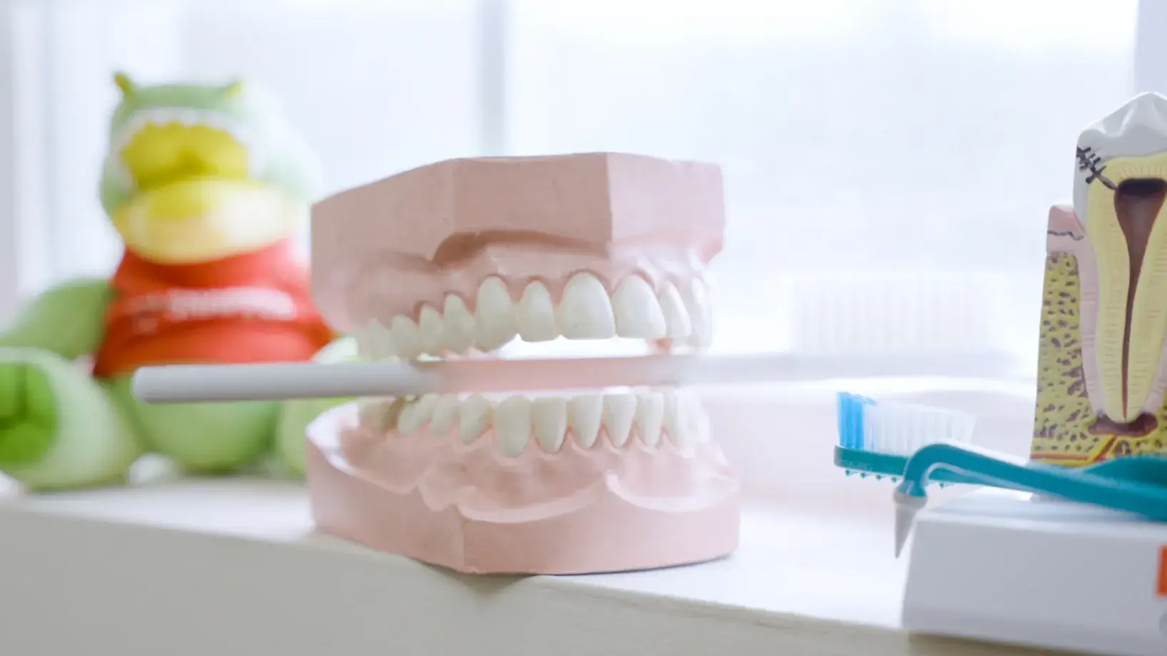 A person in scrubs points at a dental imaging machine in a clinic setting.