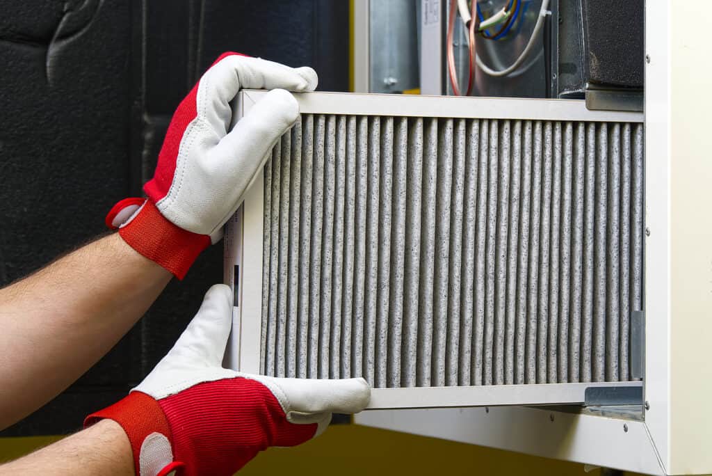 ProSolutions Inc. HVAC technician replacing the filter in a whole-home air filtration system in an Edmonton home