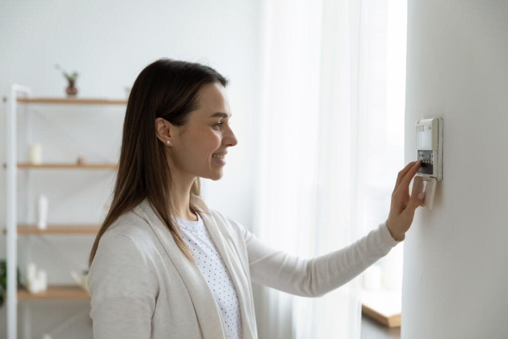 Woman adjusting thermostat to stay warm in winter