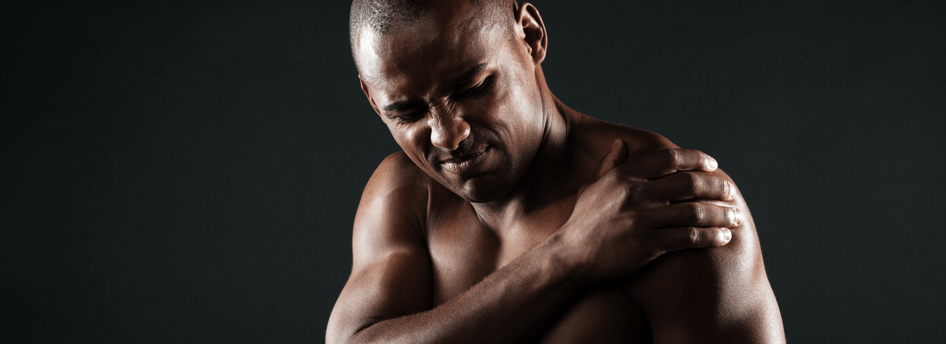 A man holds his shoulder in pain and needs to consult with the best shoulder surgeon in San Diego
