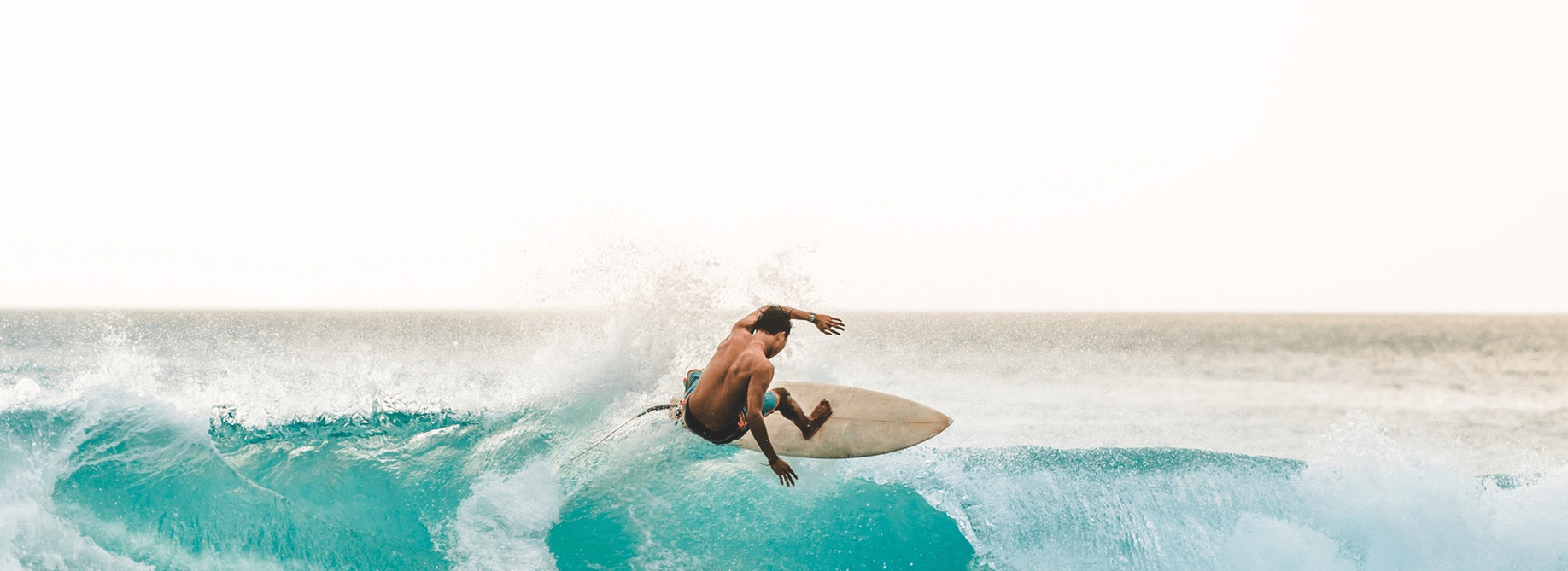 Surfer carving a turquoise wave, highlighting faster recovery from injury with BMAC and PRP from the best orthopedic doctor in San Diego for sports injury recovery.