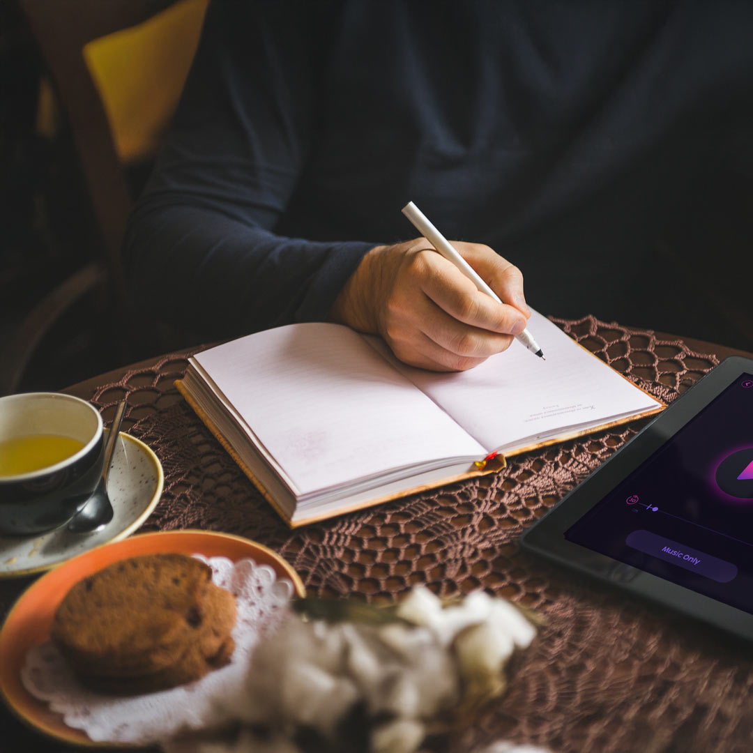 image of someone with a tea and a pastry journaling while listening to Limitless Guided Visualizations