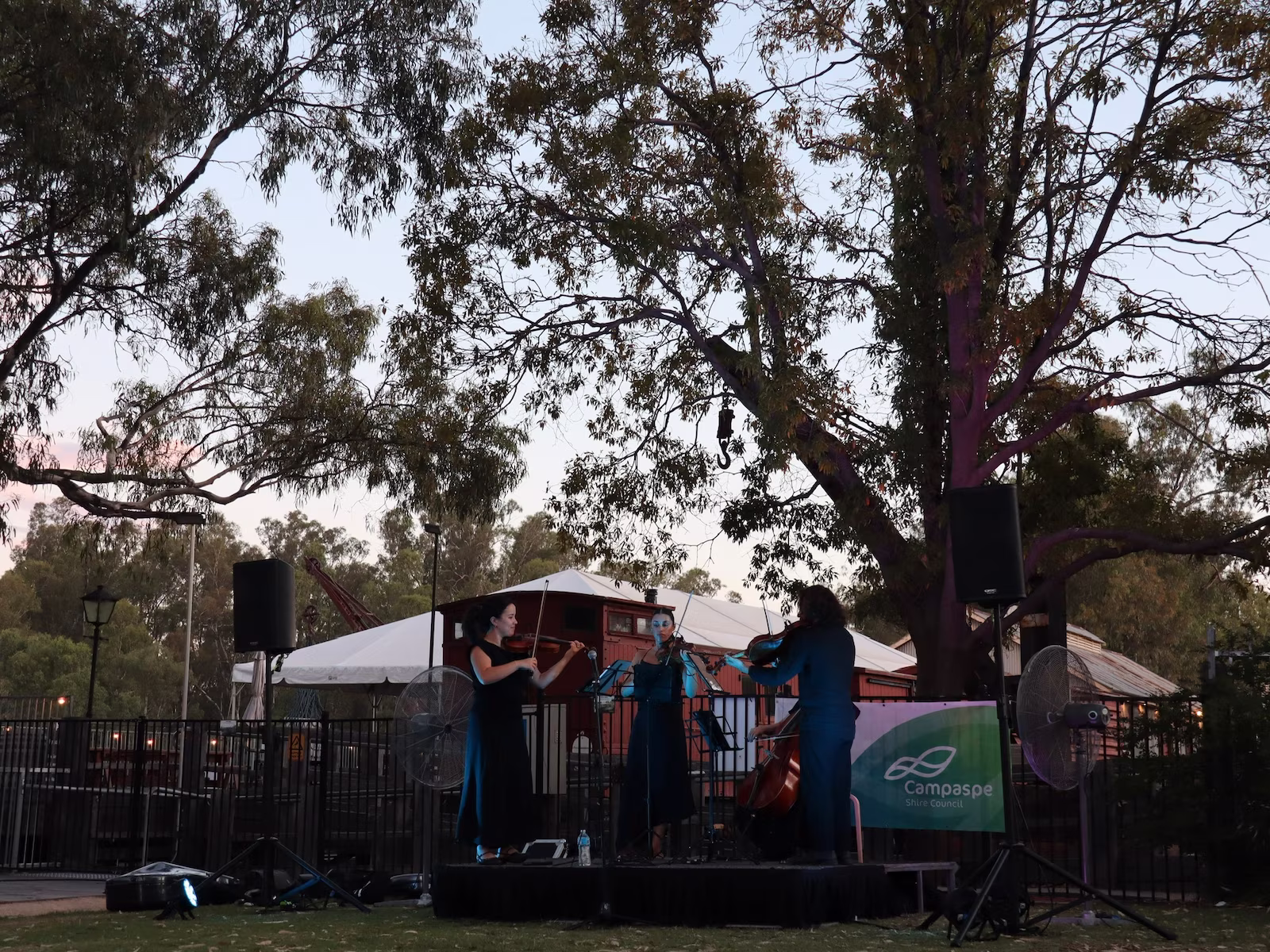 Musicians on a stage around sunset time. 