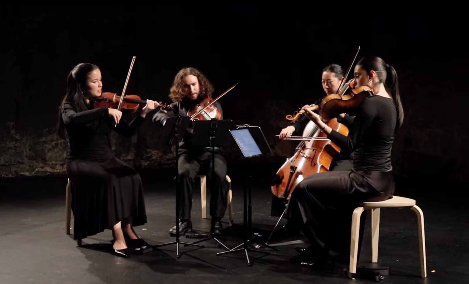 String Quartet playing in a dark concert setting.