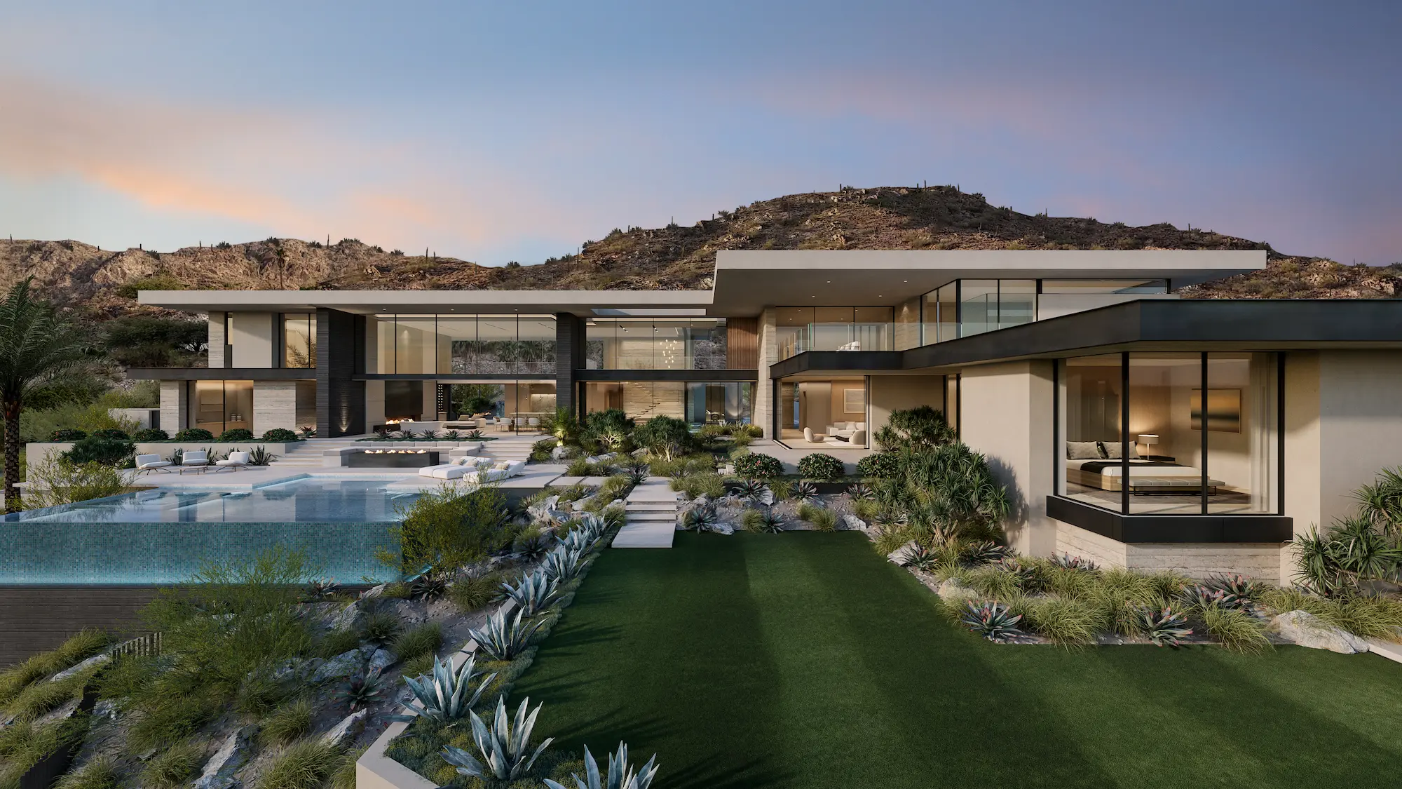 Modern luxury house with large glass windows, a pool, landscaped garden, and desert mountains in the background at dusk.