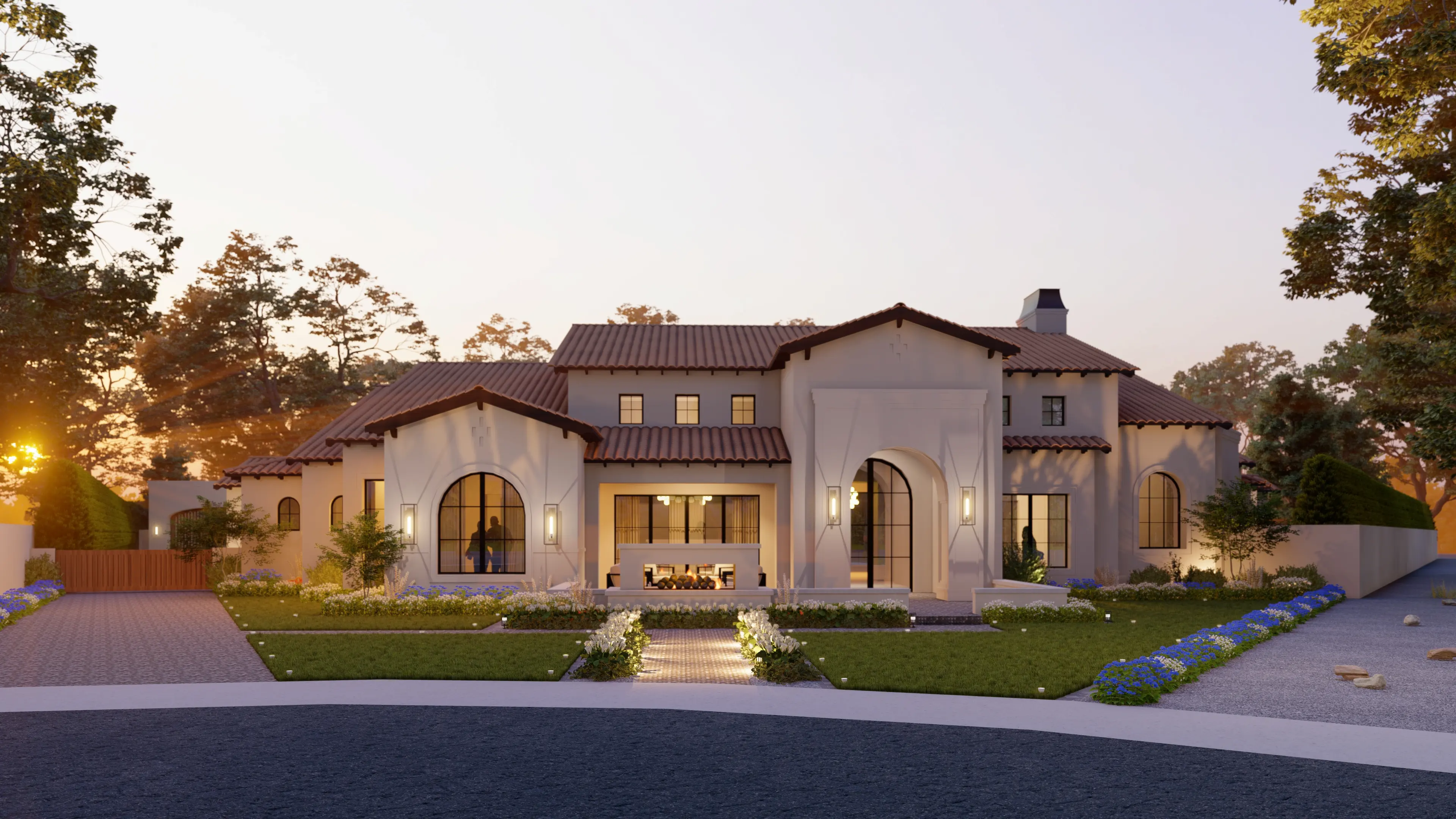 Modern large beige house with arched windows, tiled roof, front yard with lights and flowers, at sunset.