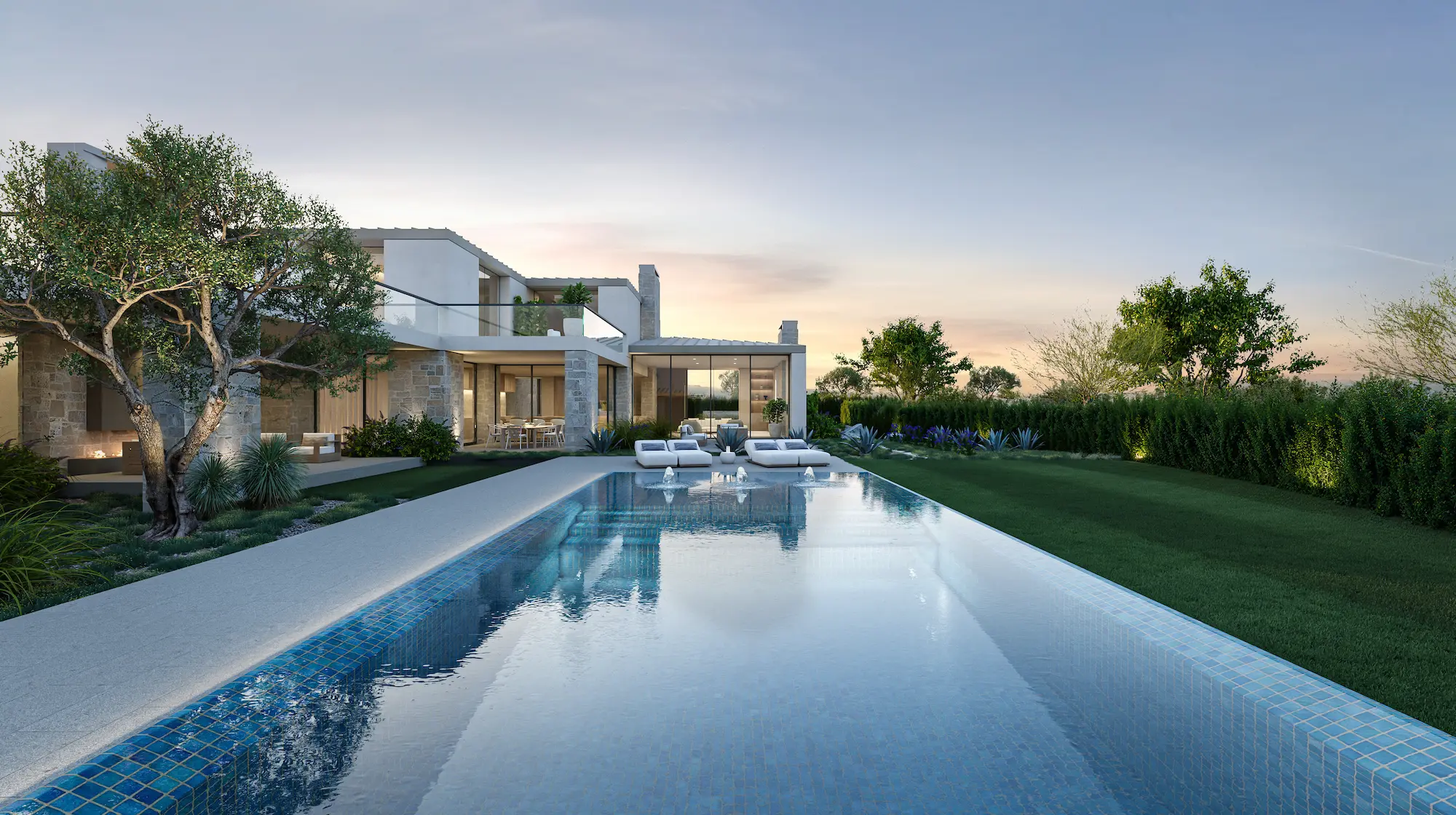 Modern luxury house with large glass windows, an infinity pool with water cascading over stone wall, lush landscaping, and mountain backdrop at dusk.