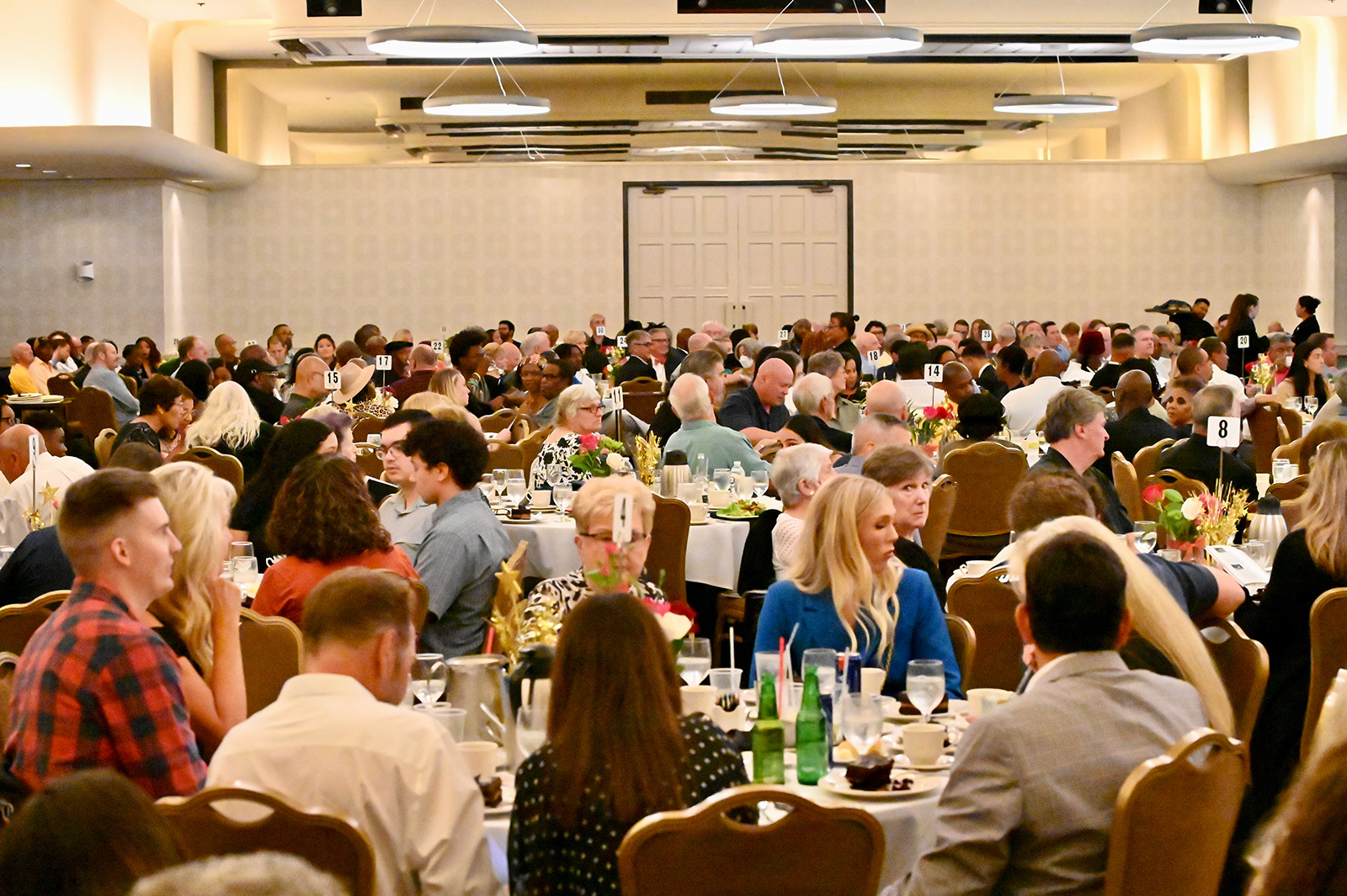 Large group of people seated at round tables in a banquet hall during a formal event.