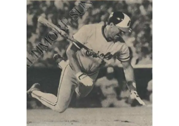 Baseball player diving headfirst while holding a bat during a game.
