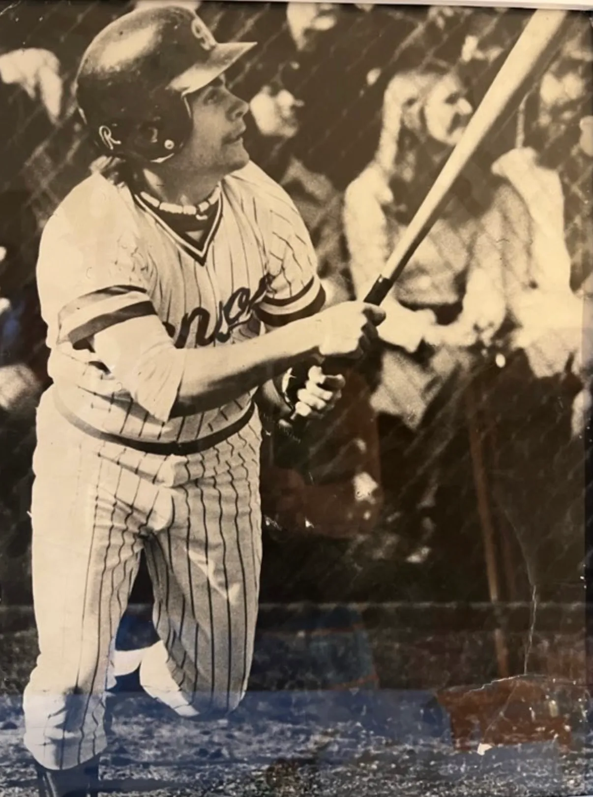 Black and white photo of a baseball player in pinstriped uniform swinging a bat during a game.