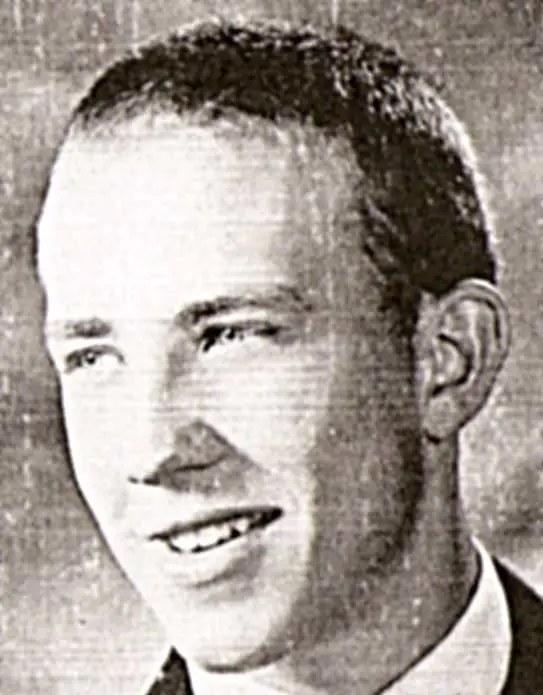 Black and white portrait of a smiling young man with short hair wearing a suit.