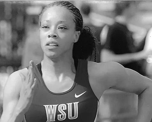 Female athlete in WSU uniform sprinting in a track and field event.