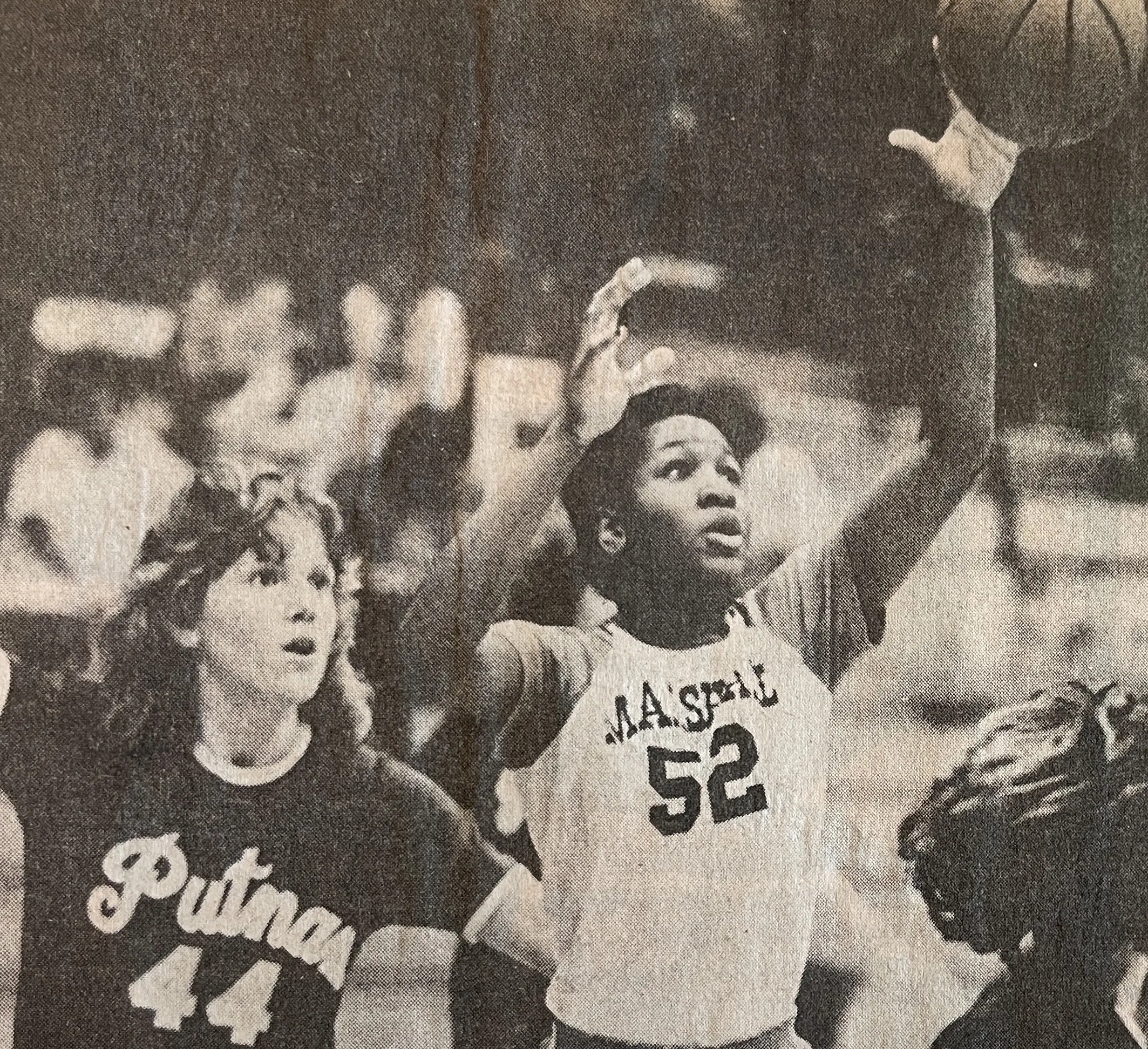 Female basketball player wearing jersey number 52 from Massillon reaching up to shoot or catch a basketball, closely defended by a player wearing jersey number 44 from Putnam.