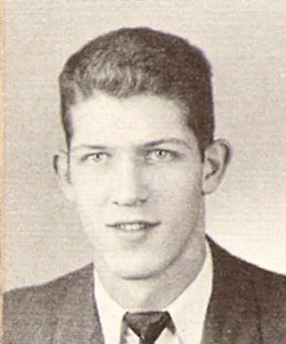 Black and white portrait of a young man with short hair wearing a suit and tie.