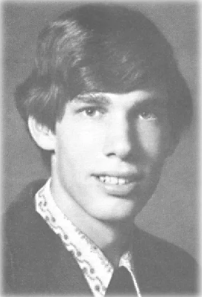 Black and white portrait of a young man with medium-length hair wearing a suit and patterned shirt.
