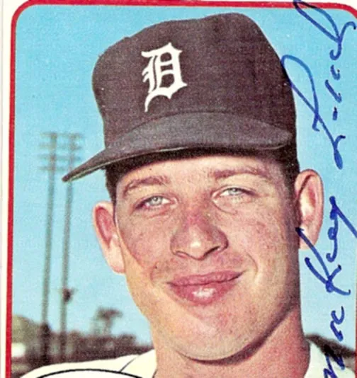 Close-up of a baseball player wearing a Detroit Tigers cap smiling with a blue sky background.