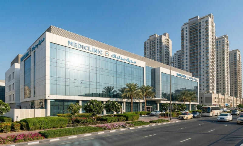 Modern hospital building exterior in Dubai with landscaping and residential towers nearby