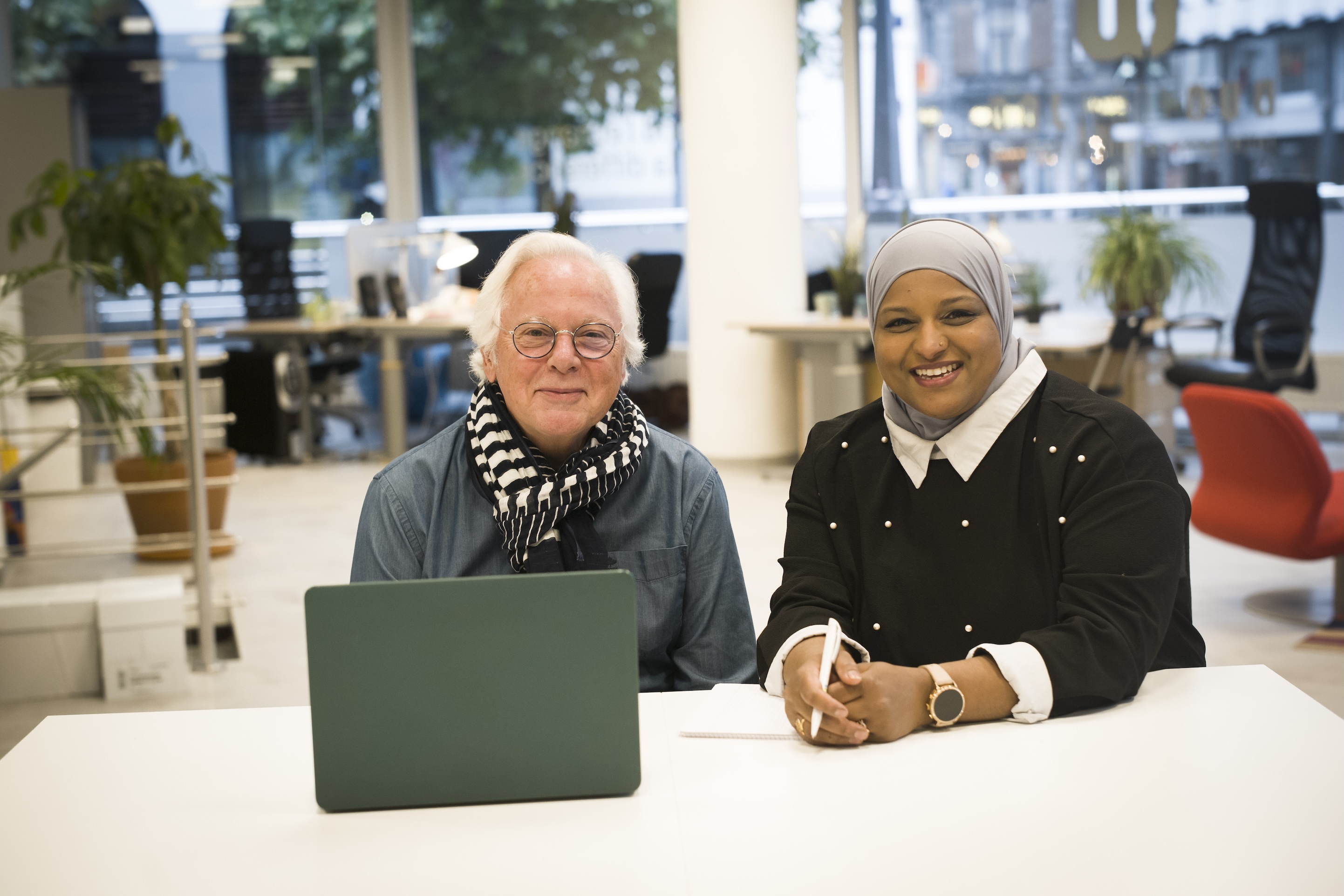 Mentor et mentee échangeant un sourire dans un cadre professionnel, illustrant le soutien et la transmission de savoir.