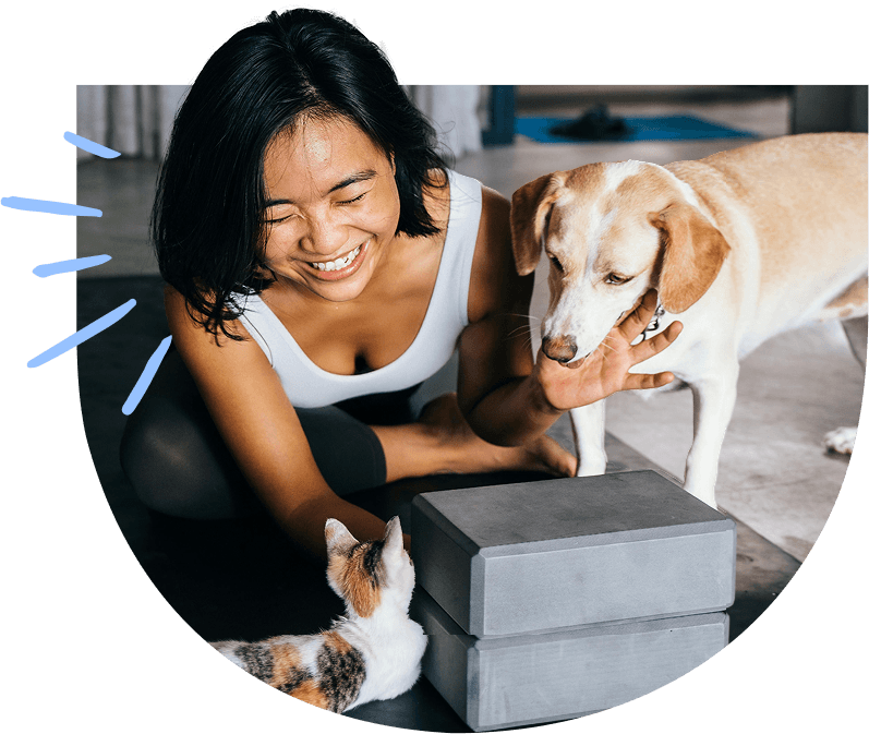 Smiling person with a cat and a dog indoors.