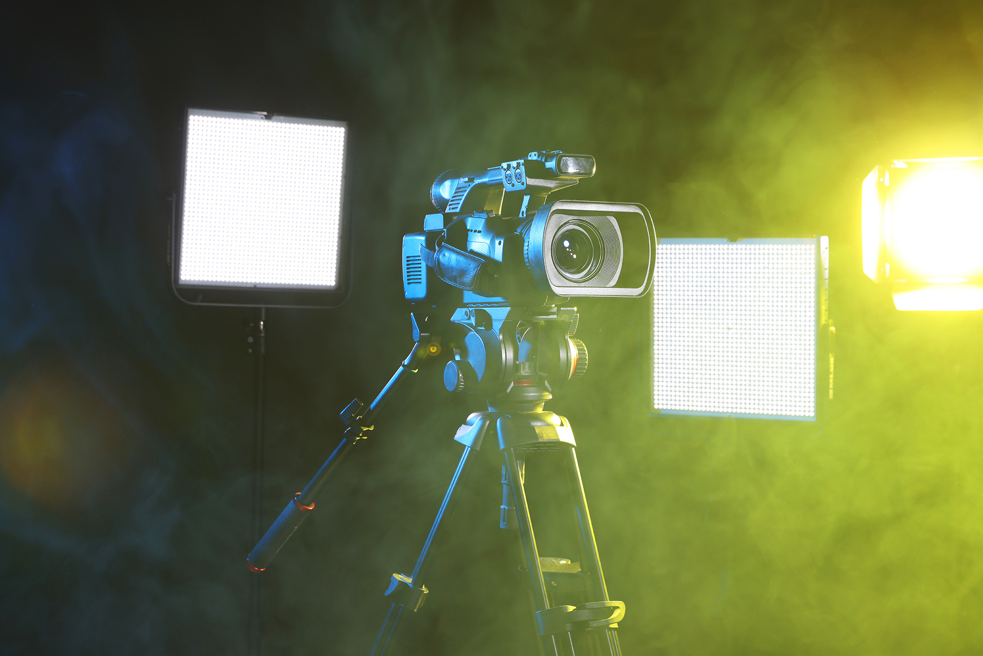 video camera on tripod with lights and smoke on stage