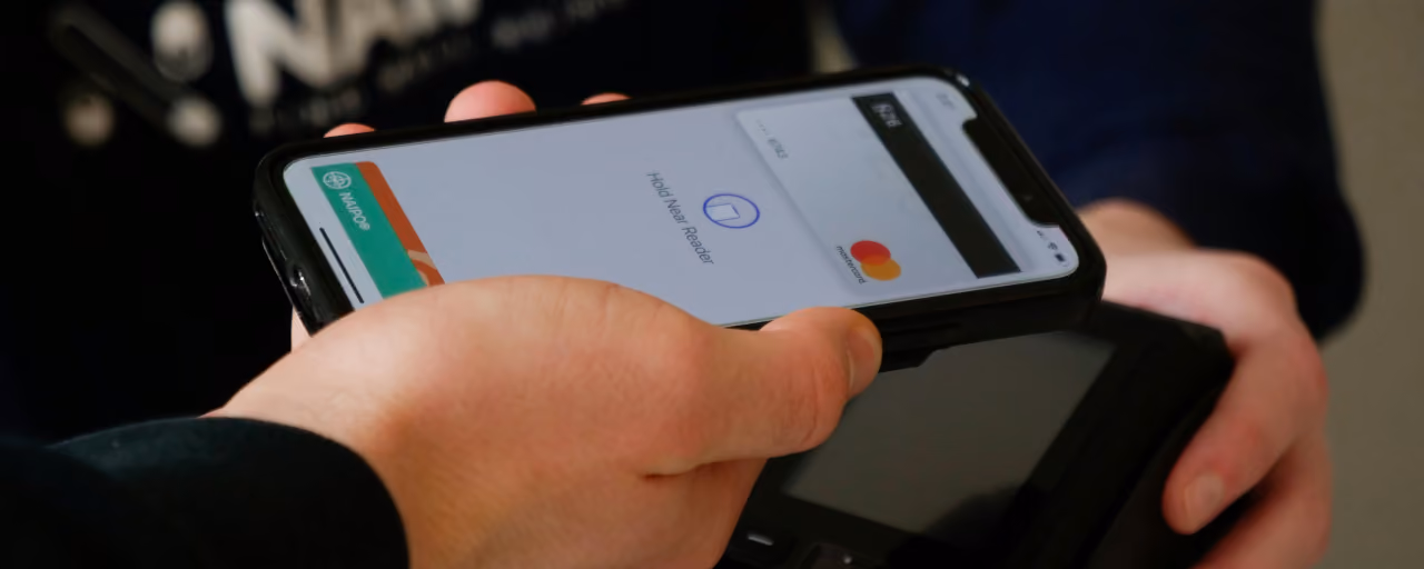 Man holding a phone with his wallet app open, tapping to pay.