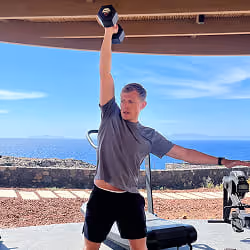 Client Whill Chapman lifting a dumbbell overhead while training.