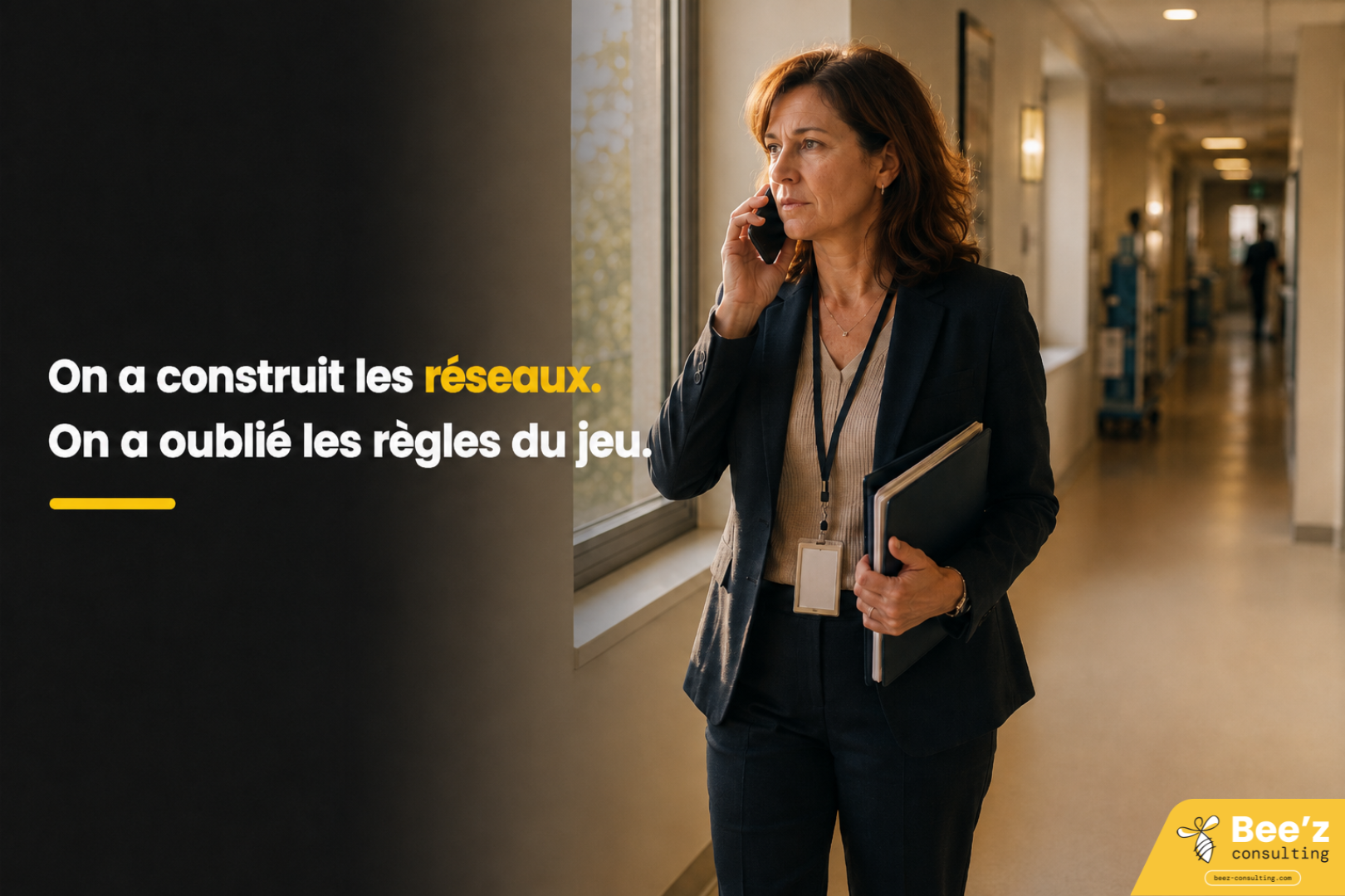 Coordinatrice de santé au téléphone dans un couloir hospitalier, tenant des documents, regard concentré vers une fenêtre.