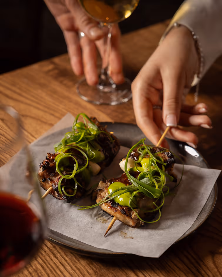 Hand taking chicken skewer showcasing Neighbourhood’s modern Irish cuisine and refined atmosphere.