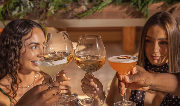 Two women clinking cocktails at dinner, captured at Neighbourhood — the best restaurant in Kildare for elevated Irish cuisine.
