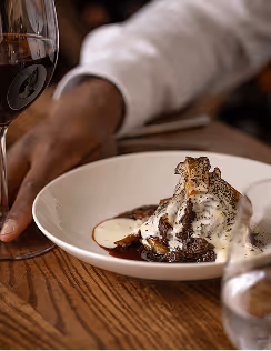 Hand serving dessert on a white plate showcasing Neighbourhood’s modern Irish cuisine and refined atmosphere.