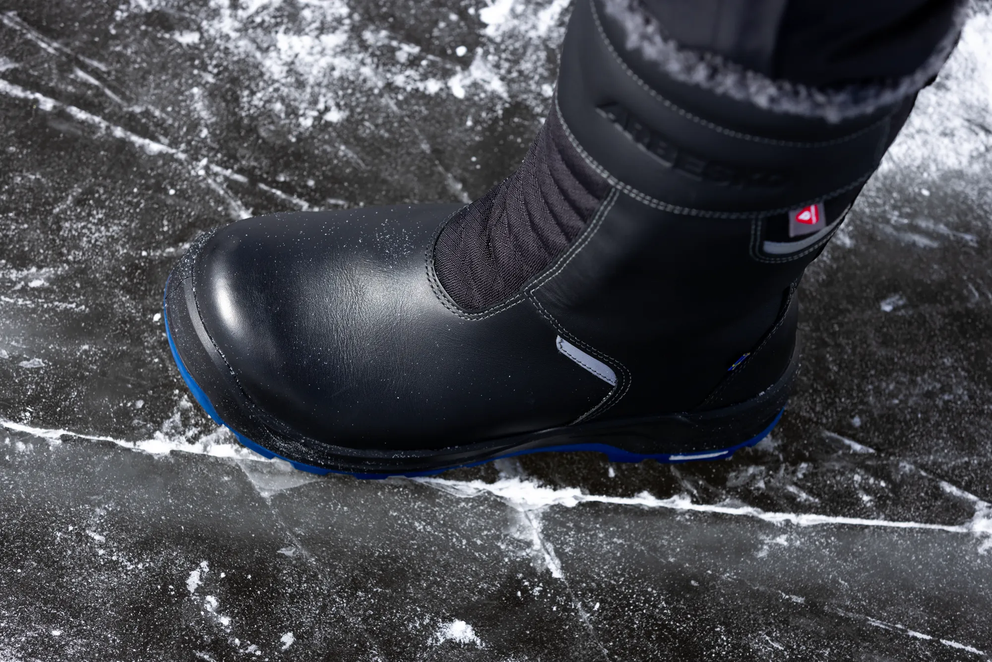 The Arbesko Kiruna 837 high-leg safety boot on a frozen ice surface with snow.