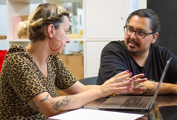 Aline Medina e Tiago Casado a discutir trabalho frente a um portátil.
