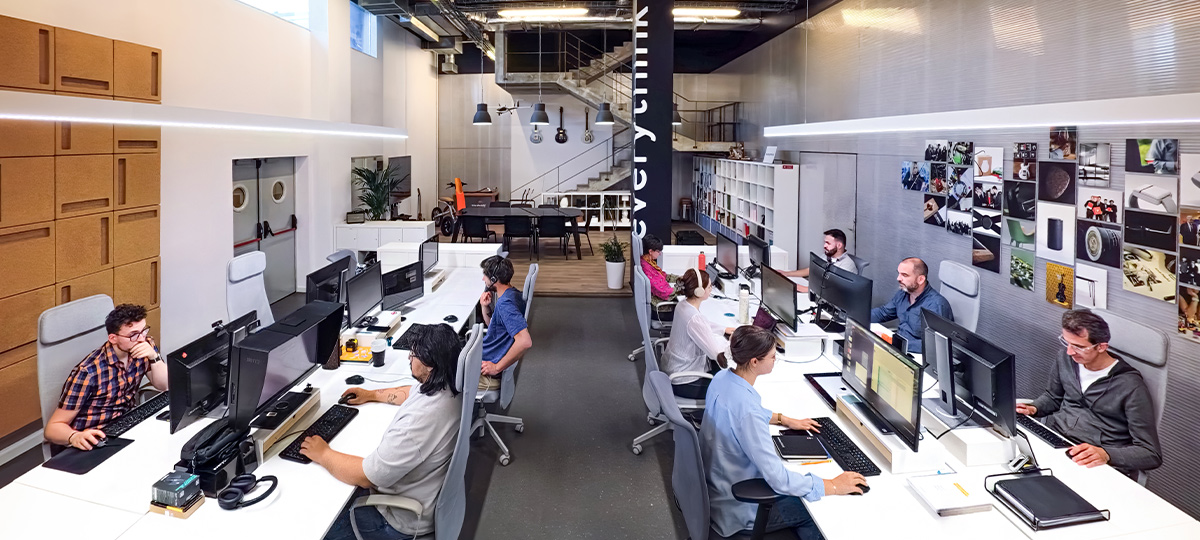 Espaço de escritório moderno com a equipa da Everythink a trabalhar em computadores num ambiente aberto e luminoso com decoração contemporânea.
