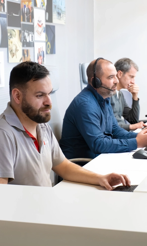 Ivo Ferreira, João Petiz e Júlio Martins sentados lado a lado trabalhando em computadores.