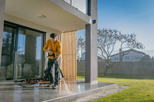 Person cleaning cement patio with a pressure washer for fast and easy outdoor concrete surface cleaning