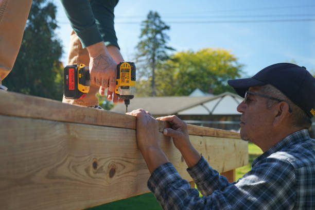Close-up of hands securing patio cover rafters with screws during DIY patio roof build