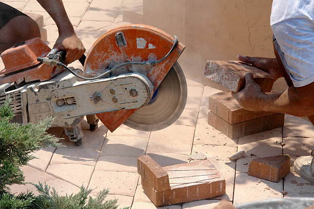 Bricks being cut to fit edges in a brick patio construction project