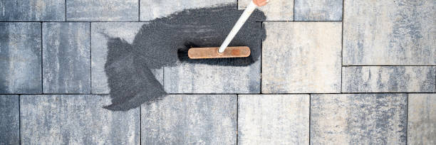 Filling paver joints with fine sand to lock stones securely