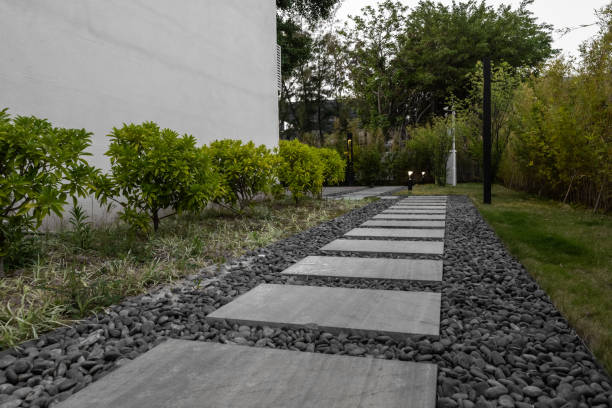 Flat concrete pavers stacked beside a garden walkway