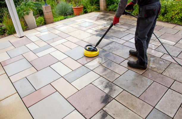 Scrubbing patio pavers with a stiff brush to remove grime