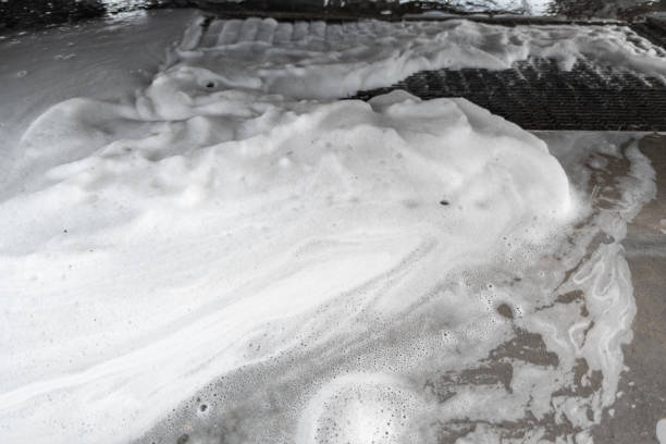 Foamy cleaning solution spread over dirty paver surface