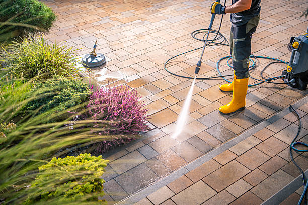 Homeowner using a pressure washer on stained patio pavers